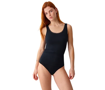 Eine Frau mit roten Haaren trägt ein schwarzes Triumph Feel Of Cotton Tank-Top mit Spitzenbesatz und schwarze Unterwäsche.