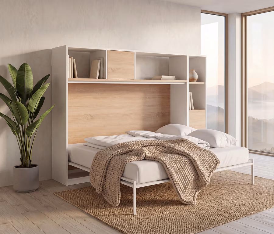 Ein weiß-holzfarbenes Roba Wandklappbett »Verso«, 120 x 200, ist in einem Raum mit großem Fenster und Bergblick ausgeklappt. Das Bett hat weiße Bettwäsche und eine beige Strickdecke. Darüber sind Regale mit Büchern und einer Vase. Links steht eine große Grünpflanze in einem grauen Topf auf einem Naturfaserteppich auf Holzboden.