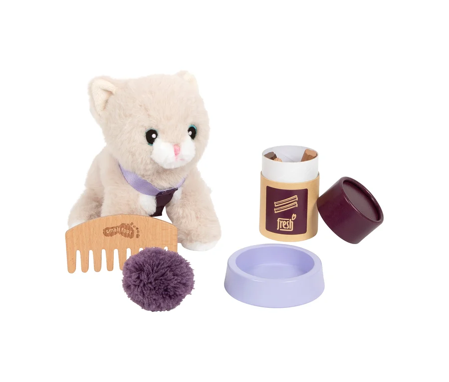 Eine hellbeige small foot Plüschkatze mit lila Halsband sitzt neben einem Holzkamm, einem lila Pompon, einem Futterbehälter mit der Aufschrift „fresh“ und einer lila Futterschale als Teil eines Pflege-Sets.