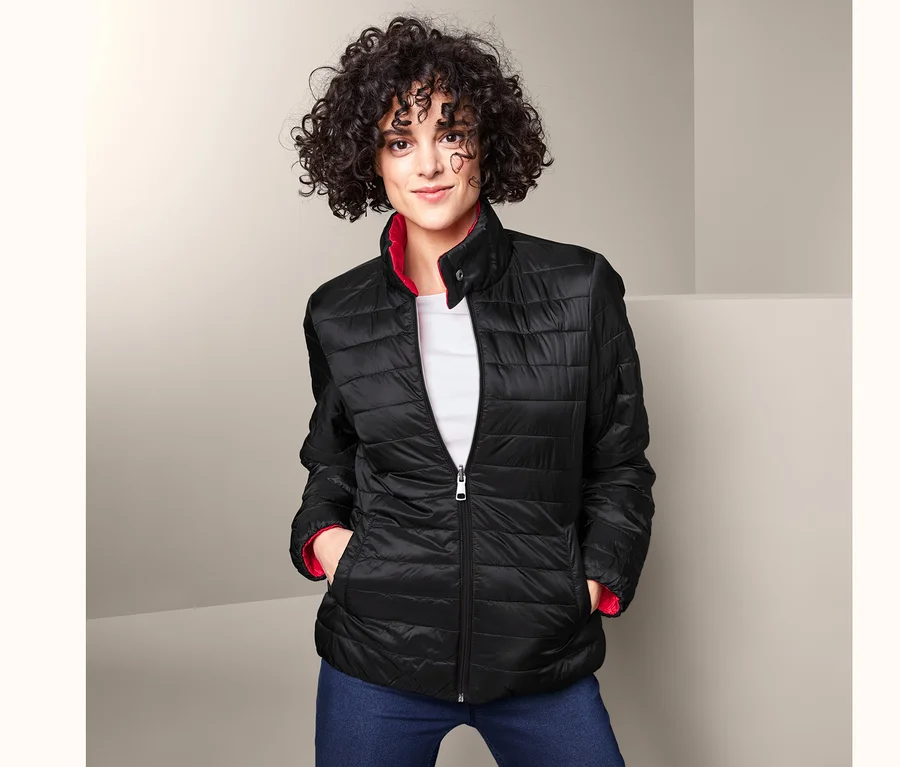 Frau trägt eine Wende-Steppjacke, Jeans und ein weißes T-Shirt.