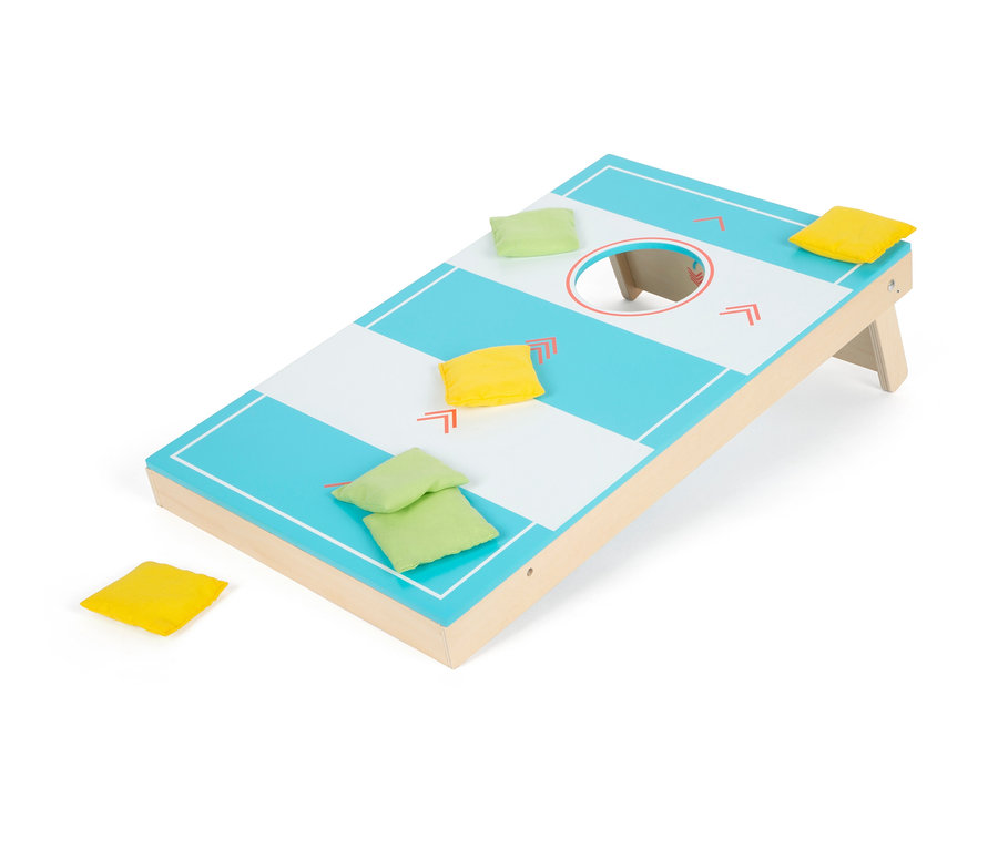 Ein Cornhole-Brett mit einem Loch und verstreuten gelben und grünen Säcken.