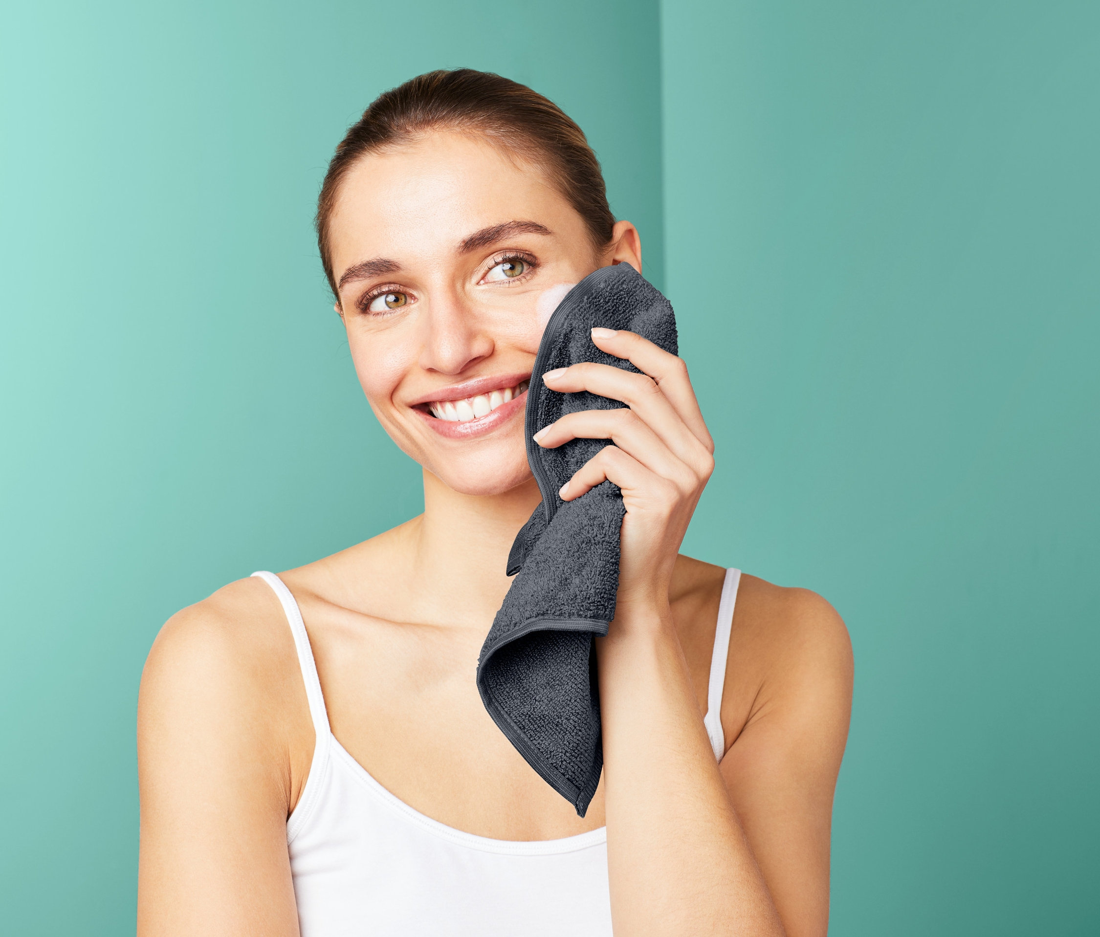 Frau reinigt ihr Gesicht mit einem grauen 3 Microfaser-Kosmetiktücher.