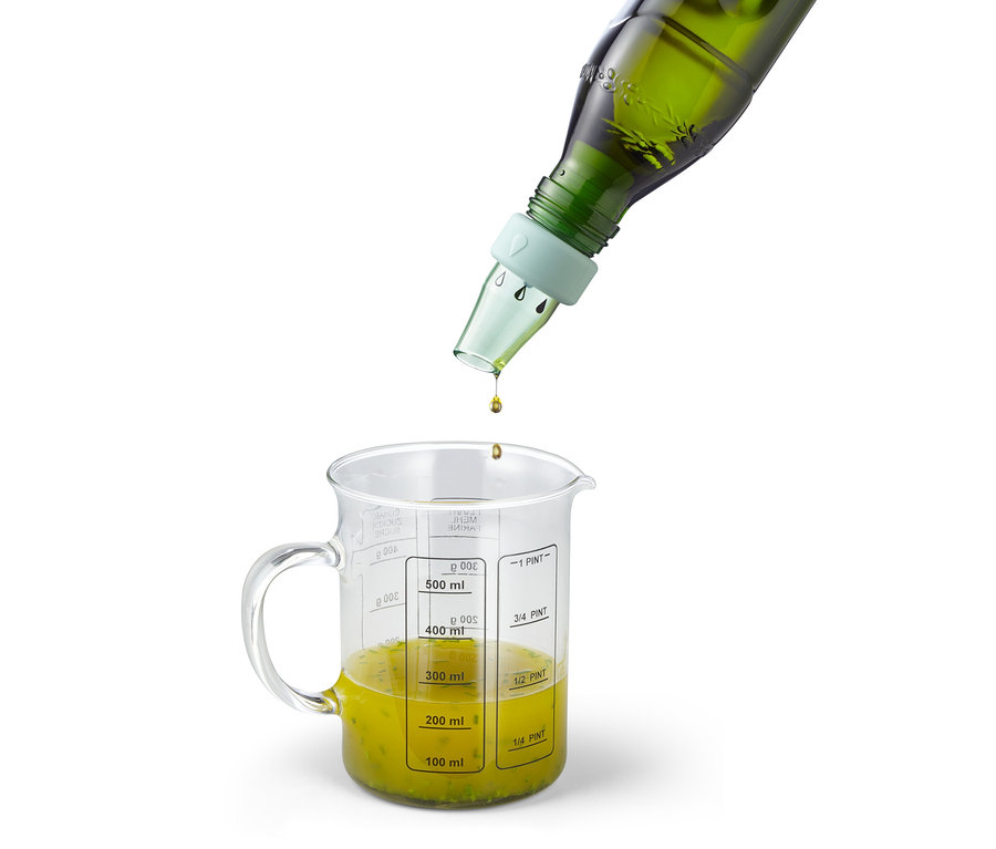 Grüne Flasche mit 2 Öl- und Essig-Flaschenaufsätzen giesst in einen Messbecher mit gelber Flüssigkeit.