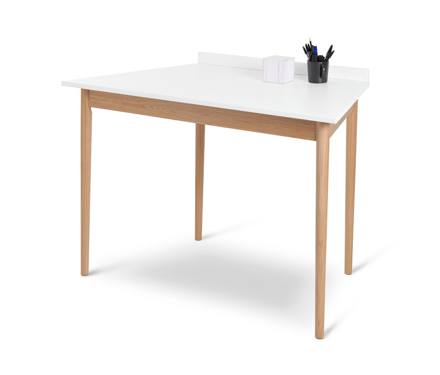 Weißer trapezförmiger Schreibtisch mit vier Holzbeinen und einer schwarzen Tasse mit Schreibutensilien.