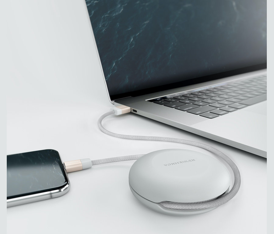 Ein Telefon und ein Notebook sind mit einem Vonmählen »Premium Cable« Ladekabel verbunden, das in einem Gehäuse aufgewickelt ist.