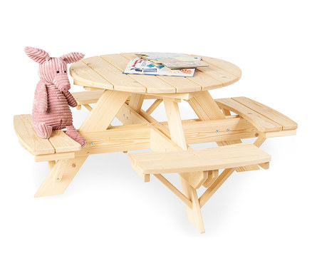 Ein rosa Stoffschwein sitzt auf einer naturfarbenen Pinolino Sitzgarnitur »Nicki für 4 rund« für Kinder mit zwei Büchern auf dem Tisch.