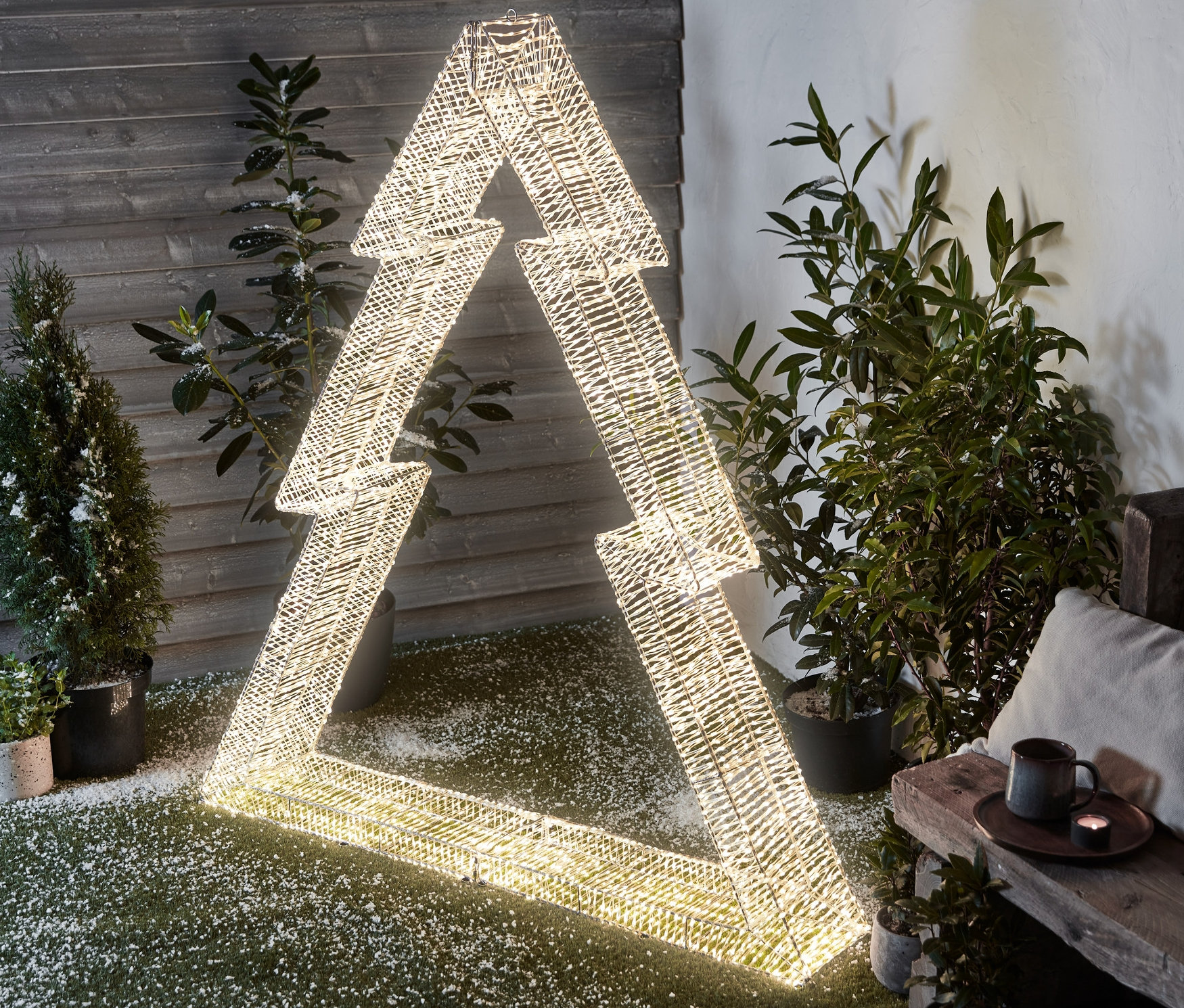 Eine beleuchtete XXL-3D-LED-Tanne steht draußen auf Kunstrasen mit Schnee.