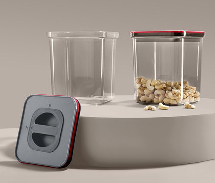 Zwei Vakuum-Frischhaltedosen, eine leer und eine mit Cashewnüssen gefüllt, sowie eine Vakuumpumpe.