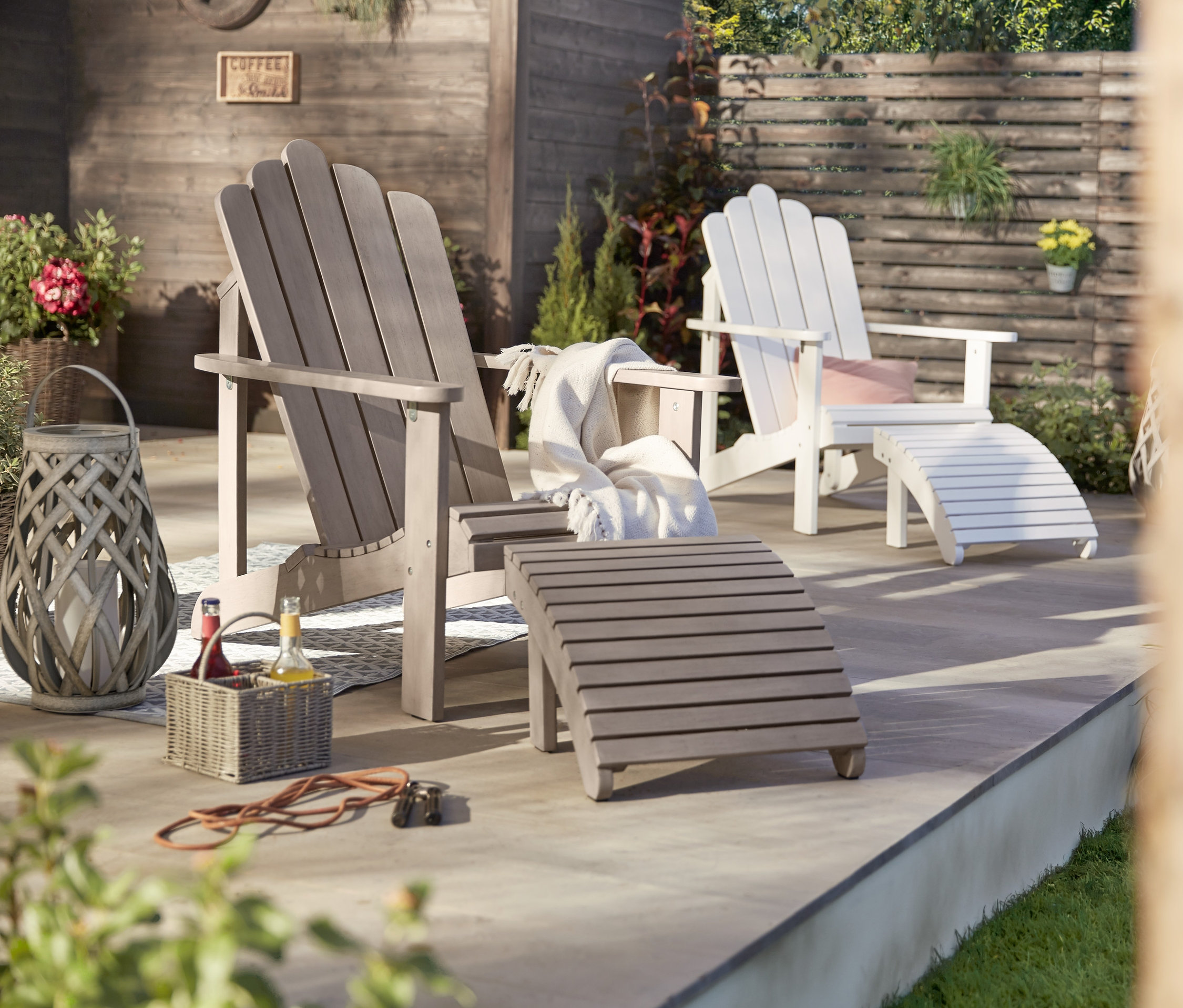 Zwei Lounge-Sessel mit separatem Fußteil, einer vintage grau, einer weiß, und eine LED-Outdoor-Laterne mit Geflecht.