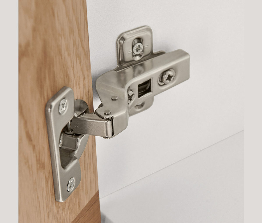 Detail eines silbernen Scharniers an einem Hochschrank mit 2 Türen.