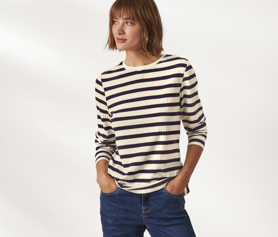 Frau posiert in geripptem Langarmshirt und Jeans.
