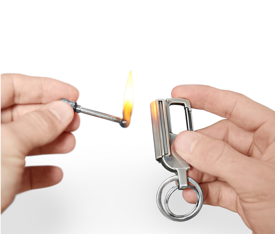 Hände halten einen Camping-Feuerstarter und zünden ihn an.