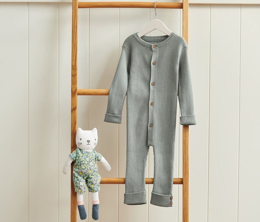 Auf einer Holzleiter hängt ein Strickoverall.