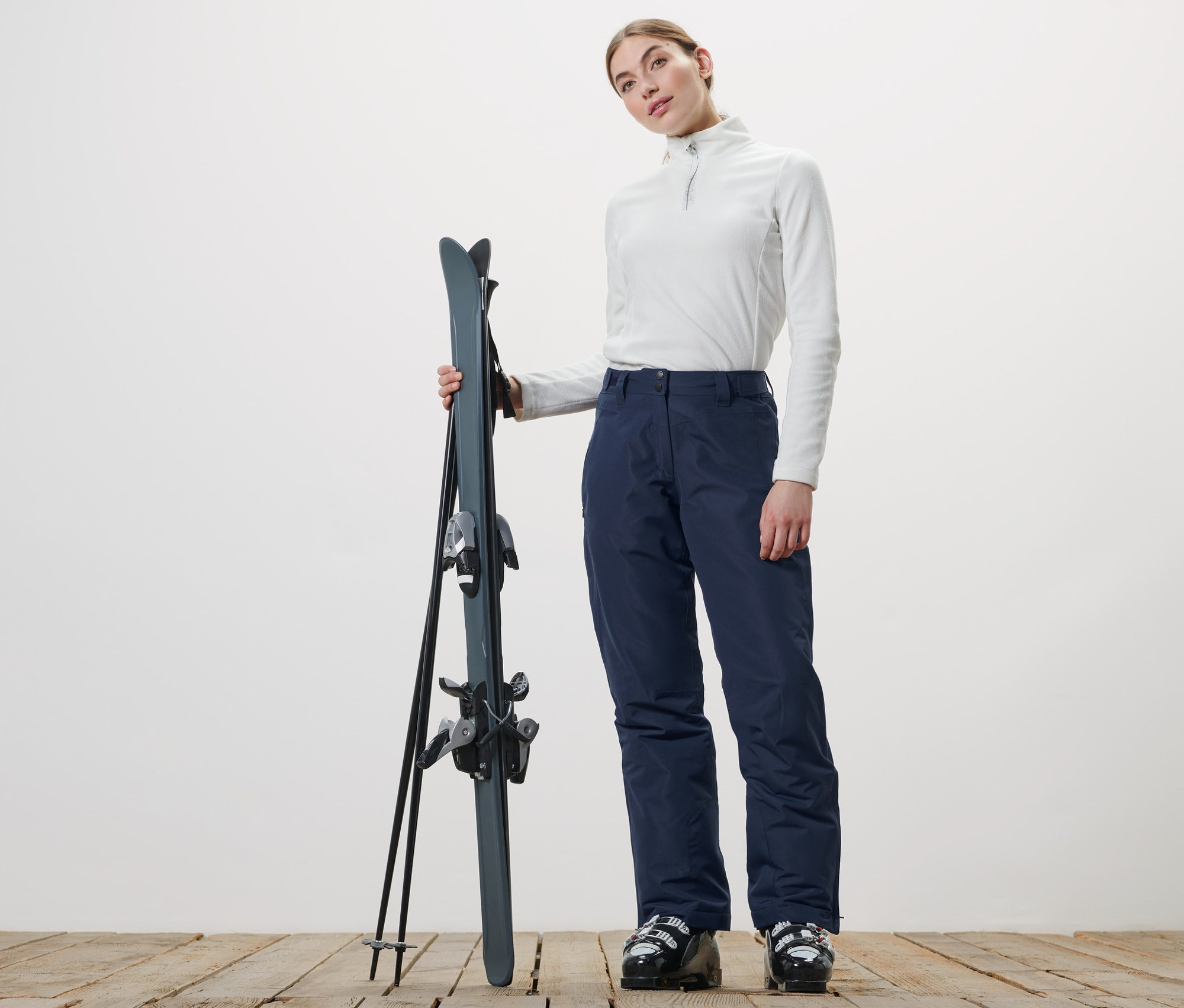 Frau hält Ski und trägt eine Skihose.