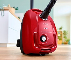 Roter Bosch BGD38RD1H Bodenstaubsauger mit Beutel auf einem Holzboden.
