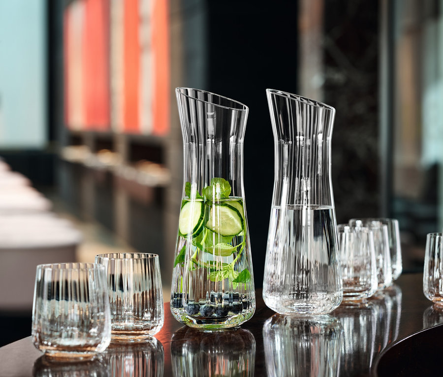 Zwei Wasserkrüge mit Obst und acht Spiegelau Bechergläser »Lifestyle«, 8er-Set auf einem Tisch.