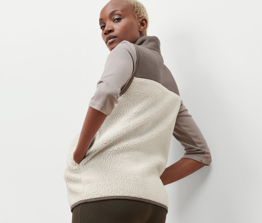 Frau posiert in einer beige-braunen Teddy-Weste.