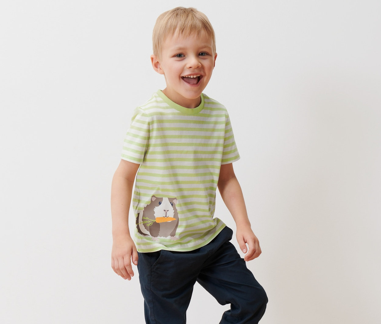 Ein Junge trägt ein kurzärmeliges, hellgrün gestreiftes T-Shirt mit einem Meerschweinchen-Motiv und 2 Kleinkind-T-Shirts.