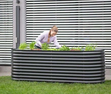 Frau arbeitet in einem ovalen Hochbeet, Breite ca. 240 cm.