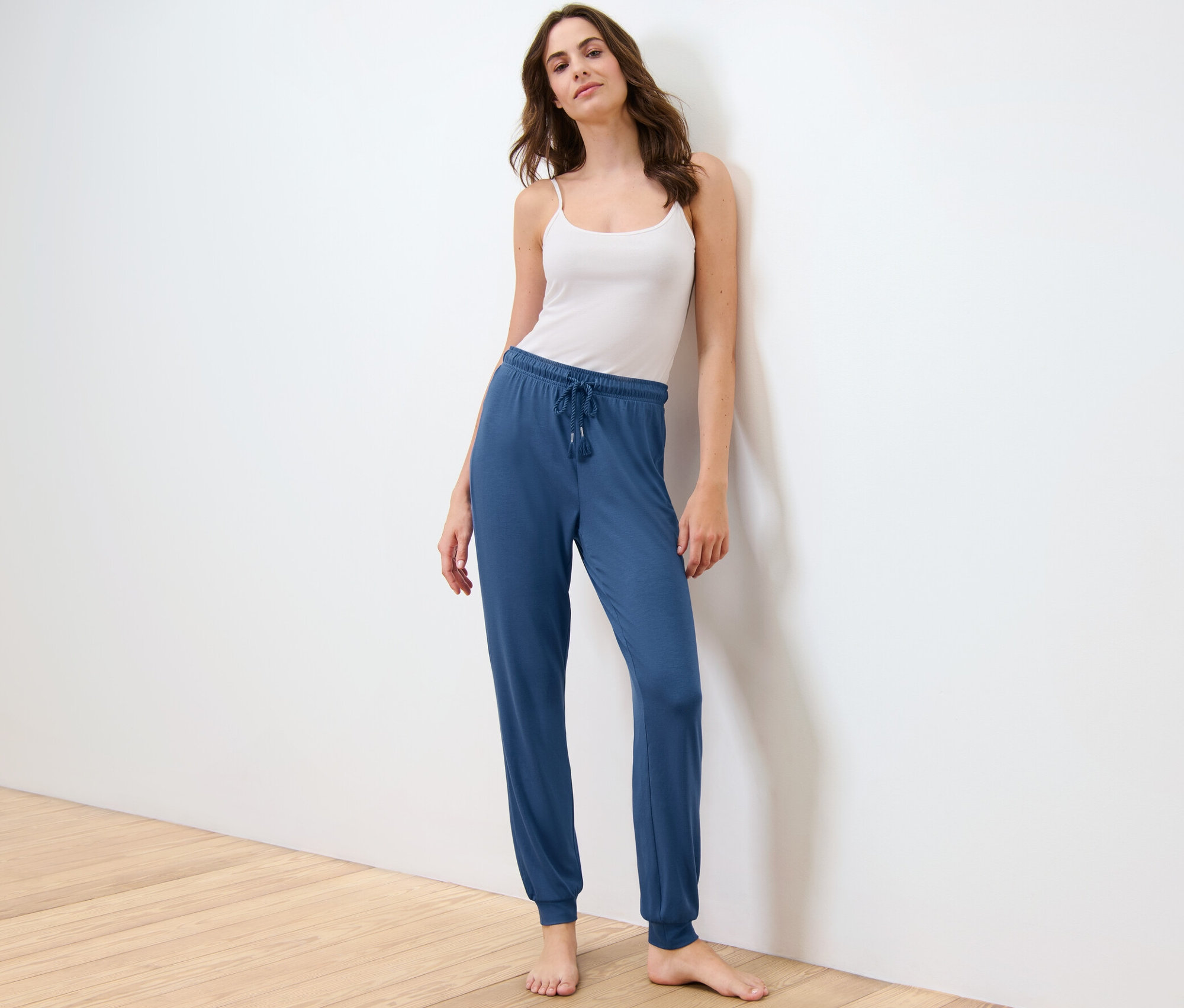 Frau posiert in Pyjamahose und Tanktop.