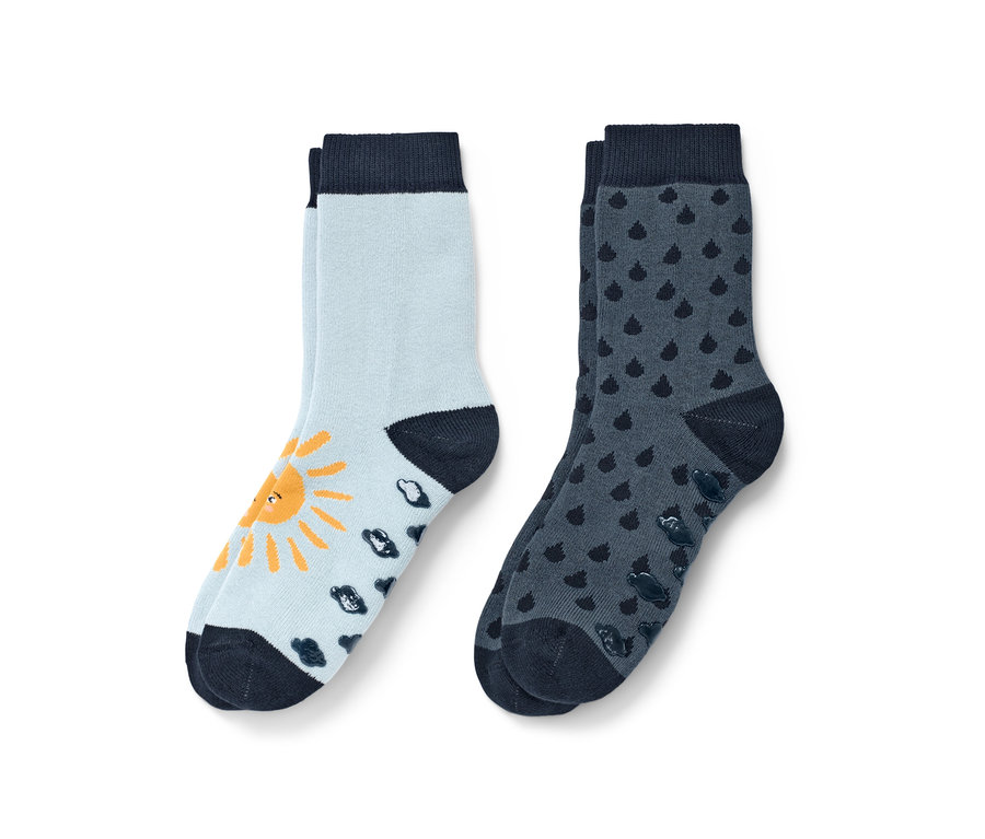 Zwei Paar blaue Kleinkind-Antirutsch-Socken. Ein Paar hellblau mit gelber Sonne und dunkelblauen Wolken, das andere dunkelblau mit Tropfen.
