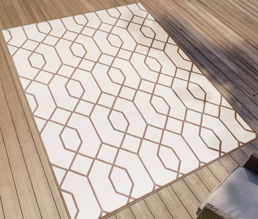 Ein brauner und weißer Outdoor-Wendeteppich »Geo River« liegt auf einem Holzdeck.