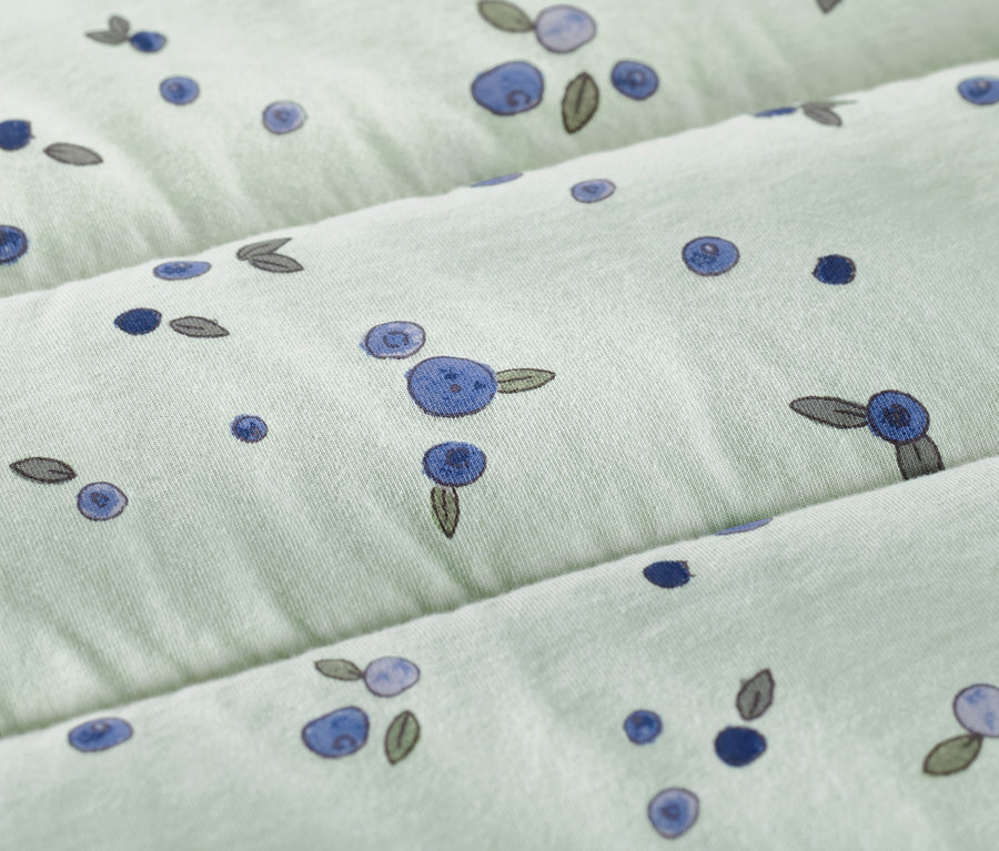 Detailansicht eines hellgrünen Schlafsacks mit Beerenmuster.