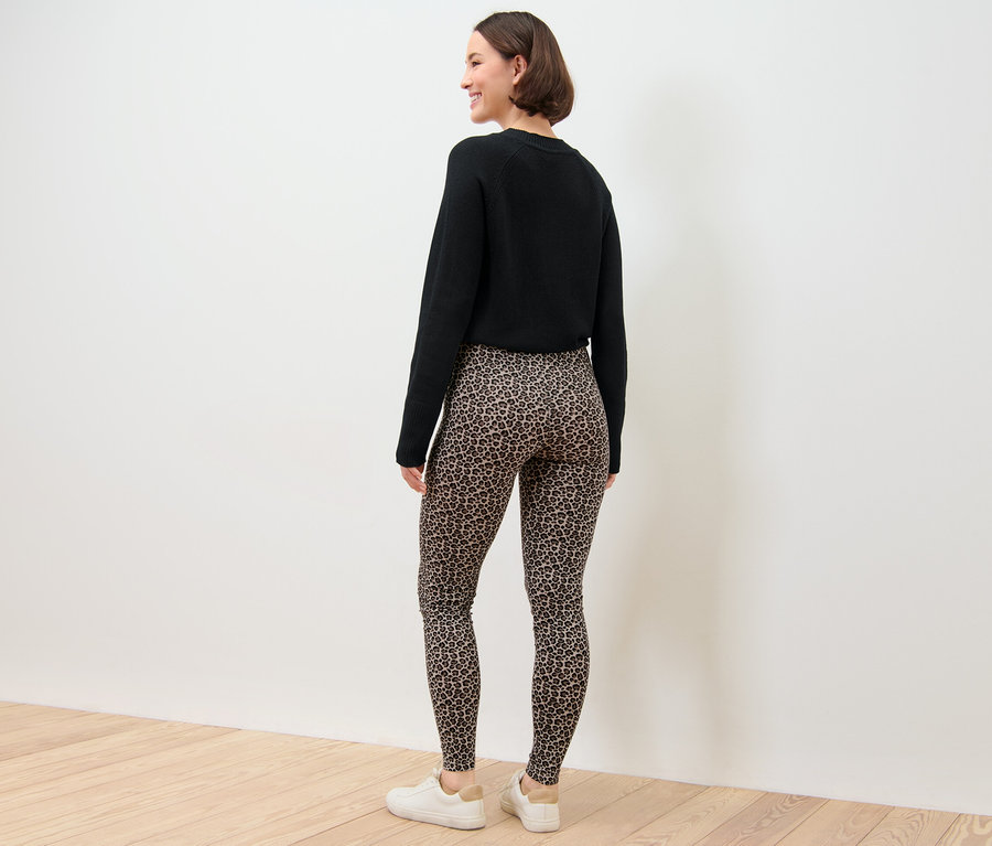 Frau trägt einen schwarzen Pullover und bedruckte Leggings.
