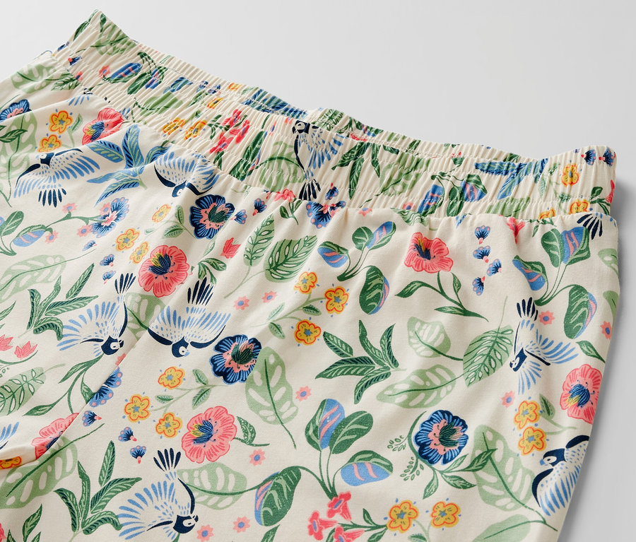 Detailansicht eines Pyjama-Sets mit Blumen- und Vogelmuster.