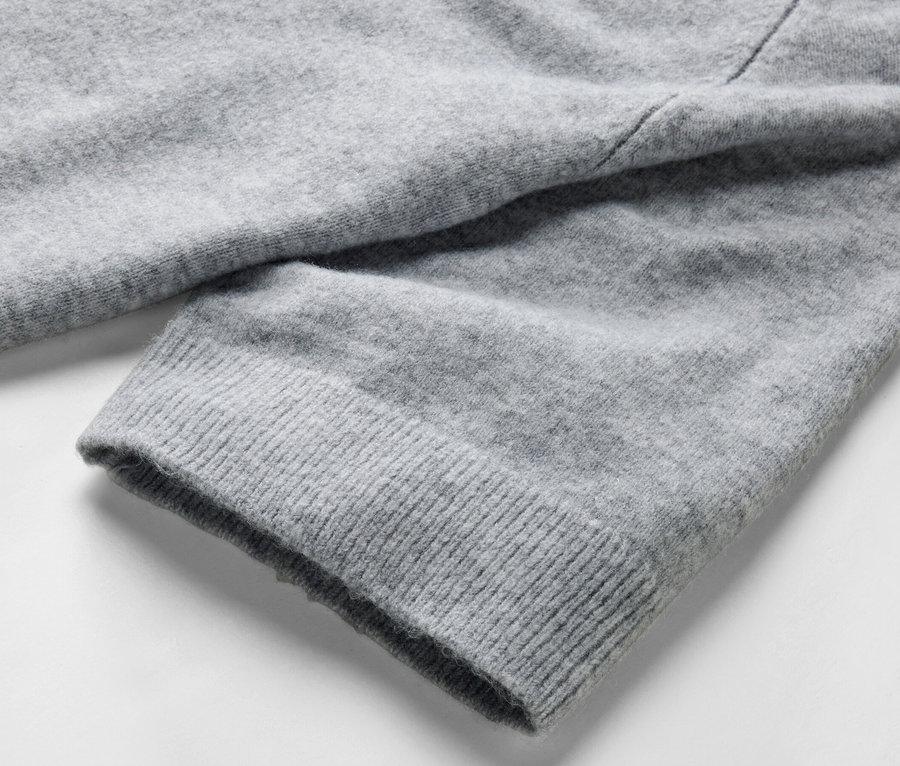 Detailansicht eines grauen Strickpullovers.
