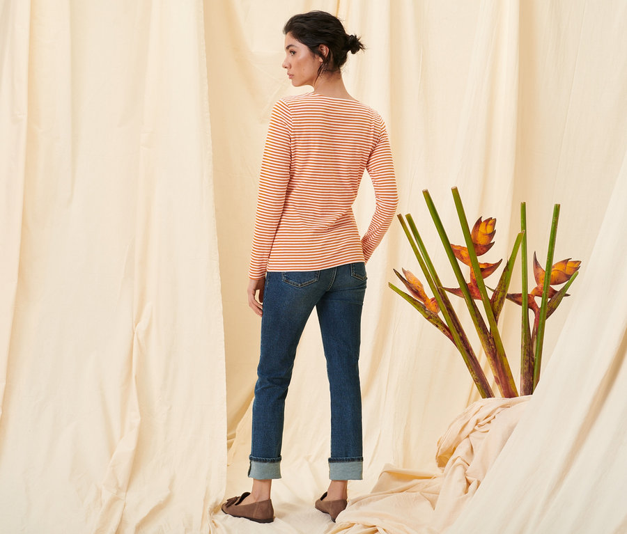 Frau steht mit dem Rücken zur Kamera und trägt ein gestreiftes Langarmshirt in Orange, Straight-Denim »Fit Kira« und Loafer aus Veloursleder.