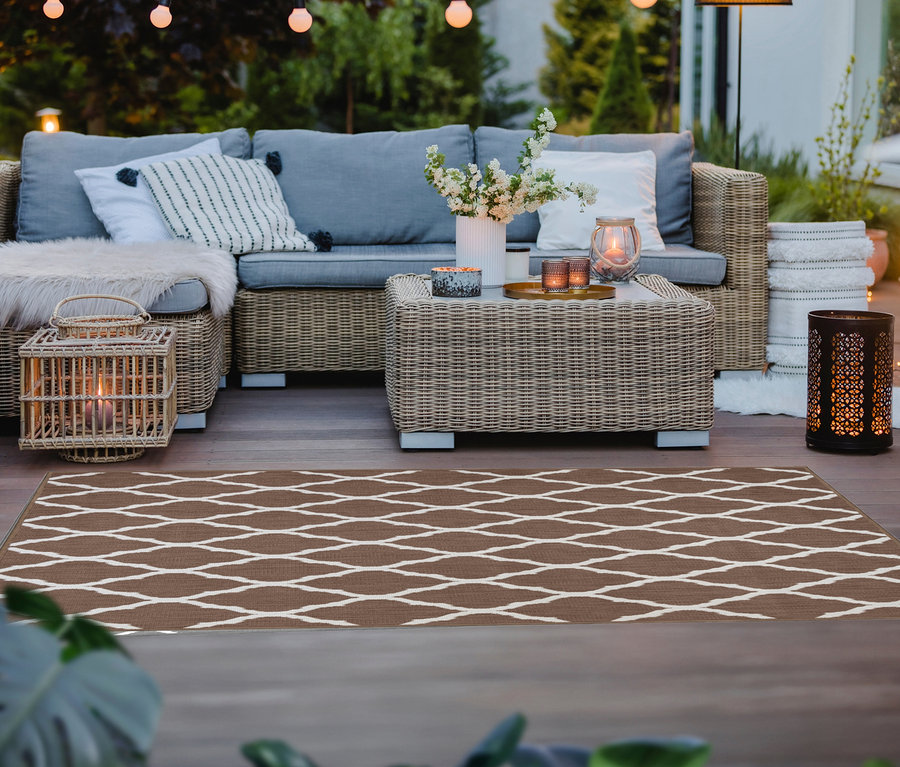 Ein brauner Outdoor-Wendeteppich »Rhombus« mit weißem geometrischen Muster liegt auf einer Holzterrasse.