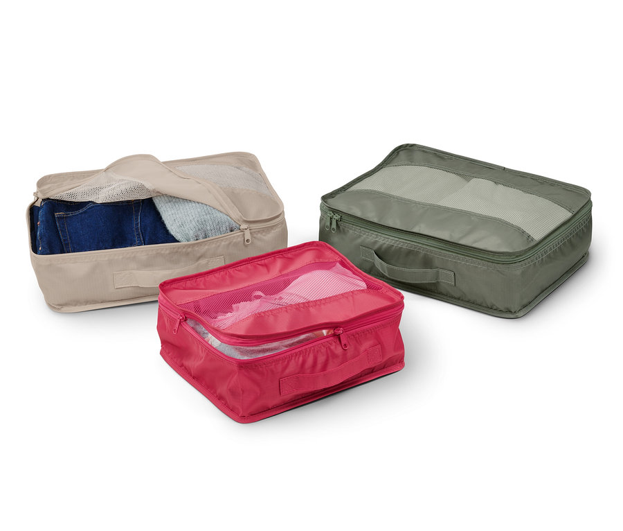 Drei Reiseordnungstaschen in Beige, Pink und Grün, jeweils mit Inhalt und Netzdeckel.