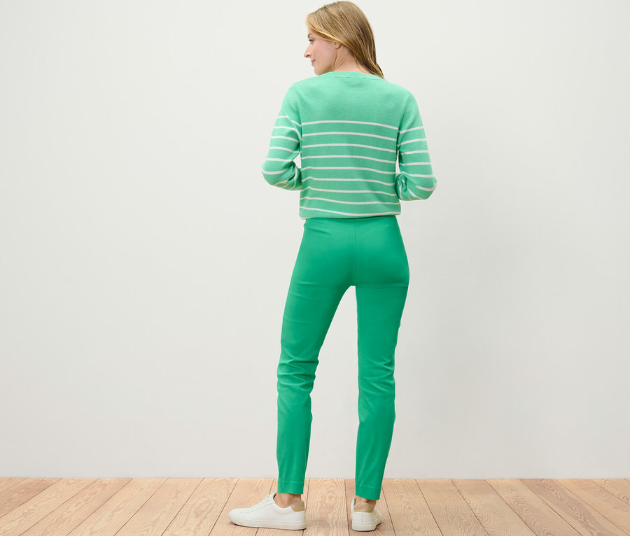 Frau steht mit dem Rücken zur Kamera und trägt eine grüne Stretchhose.