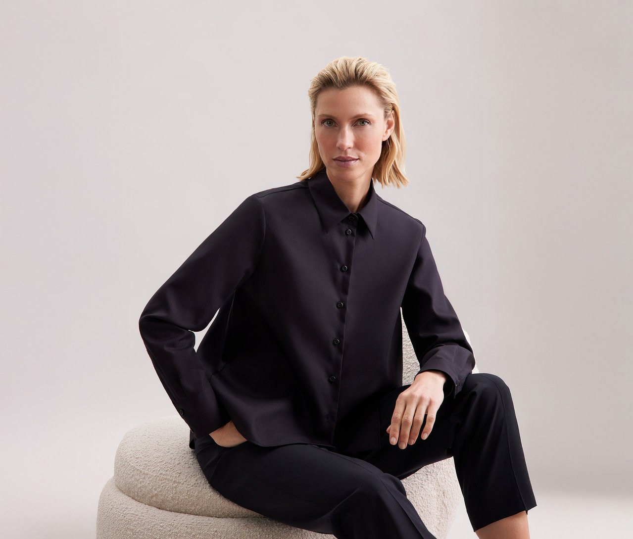 Frau sitzt und trägt eine Seidensticker Regular-Bluse.