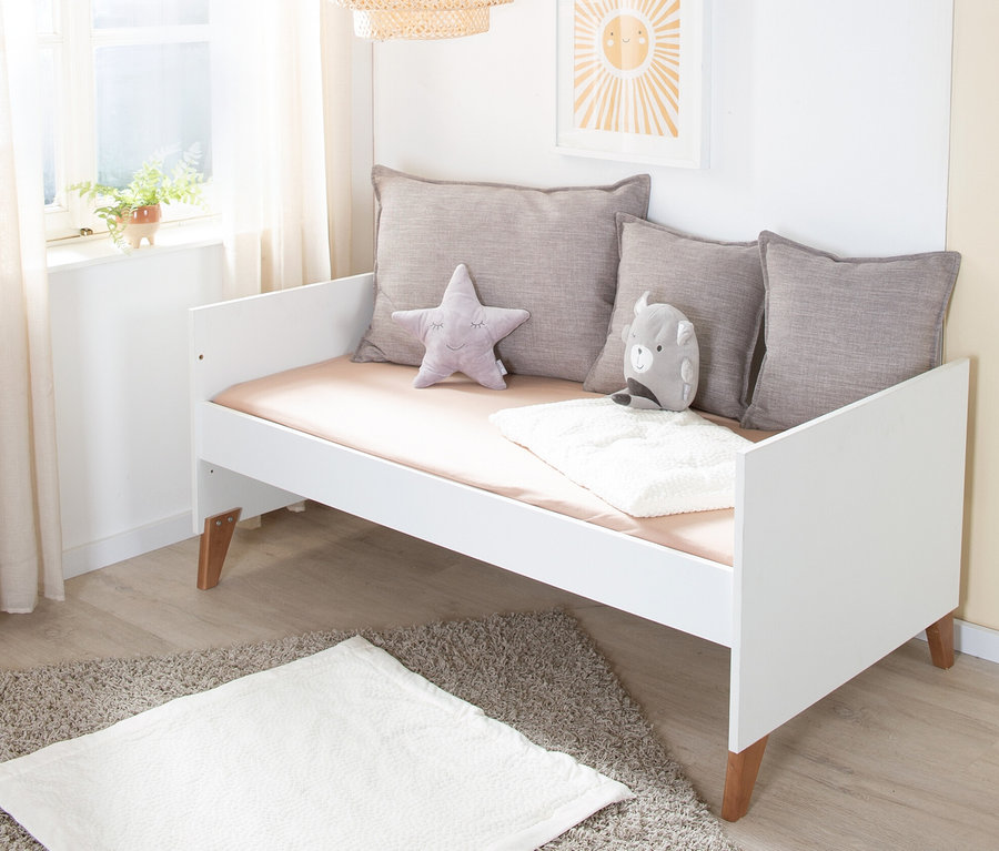 Weißes Kinderbett mit grauen Kissen und Spielsachen auf der Matratze, Lampe und Bild der Sonne hängen über dem Bett. roba »Ole« Kinderzimmerset Bett und Wickelkommode.