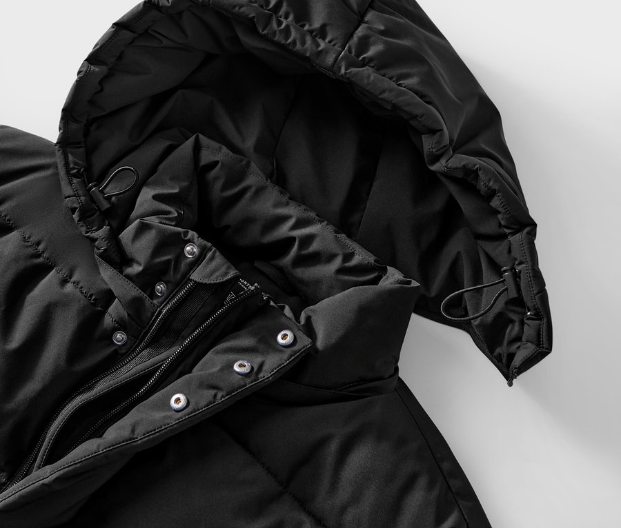 Detailaufnahme einer schwarzen Steppjacke mit Kapuze und Reißverschluss.