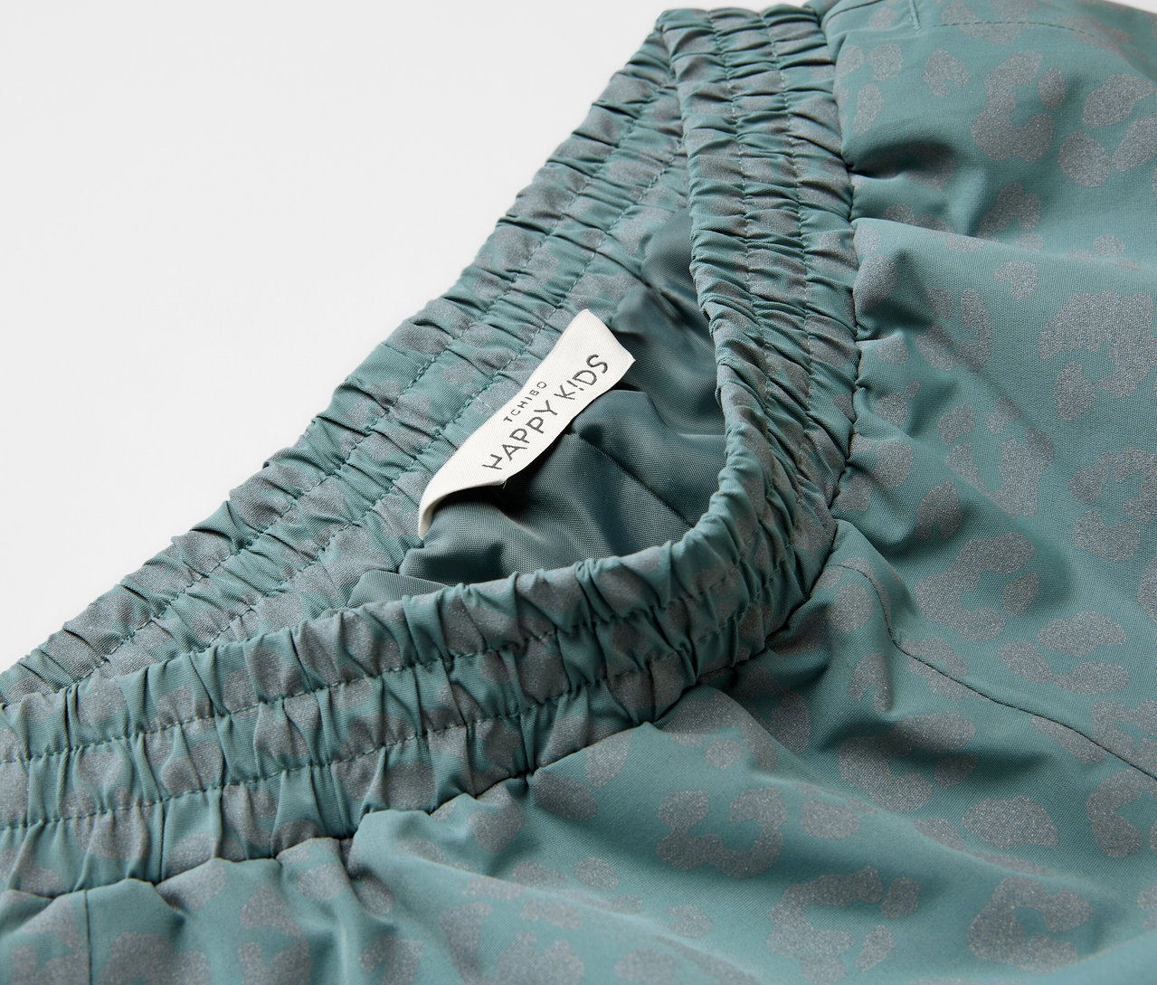 Nahaufnahme einer Kinder-Regenhose mit reflektierenden Elementen, elastischem Bund und Happy Kids-Etikett.