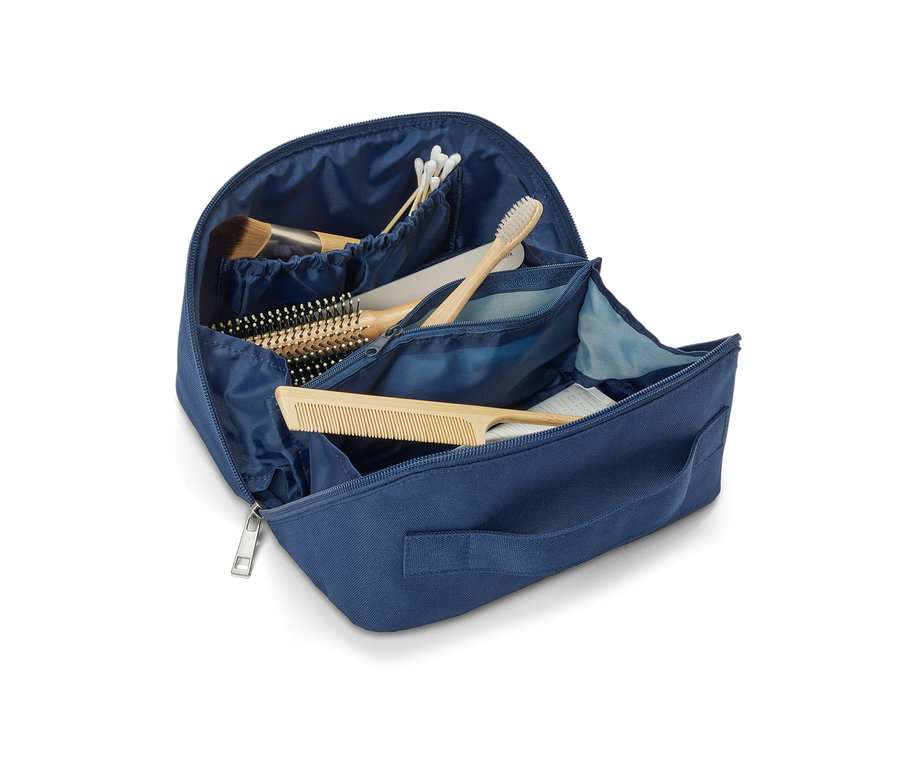 Geöffnete blaue Kosmetiktasche mit Kamm, Bürste, Make-up Pinsel und Zahnbürste.