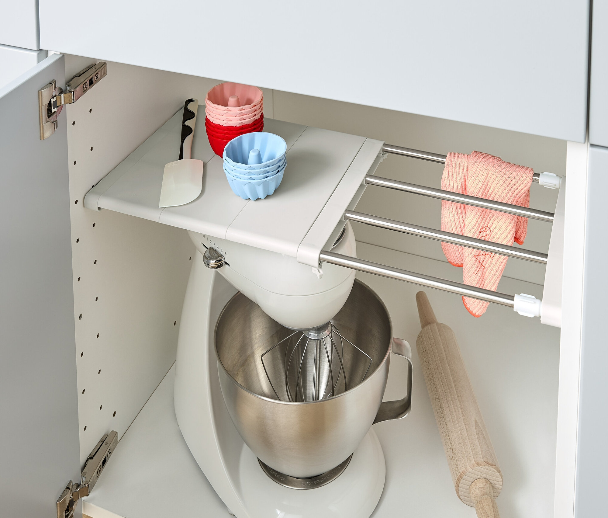 In einem Küchenschrank befinden sich ein flexibler Regalboden, eine Küchenmaschine, eine Teigrolle und Silikonförmchen.