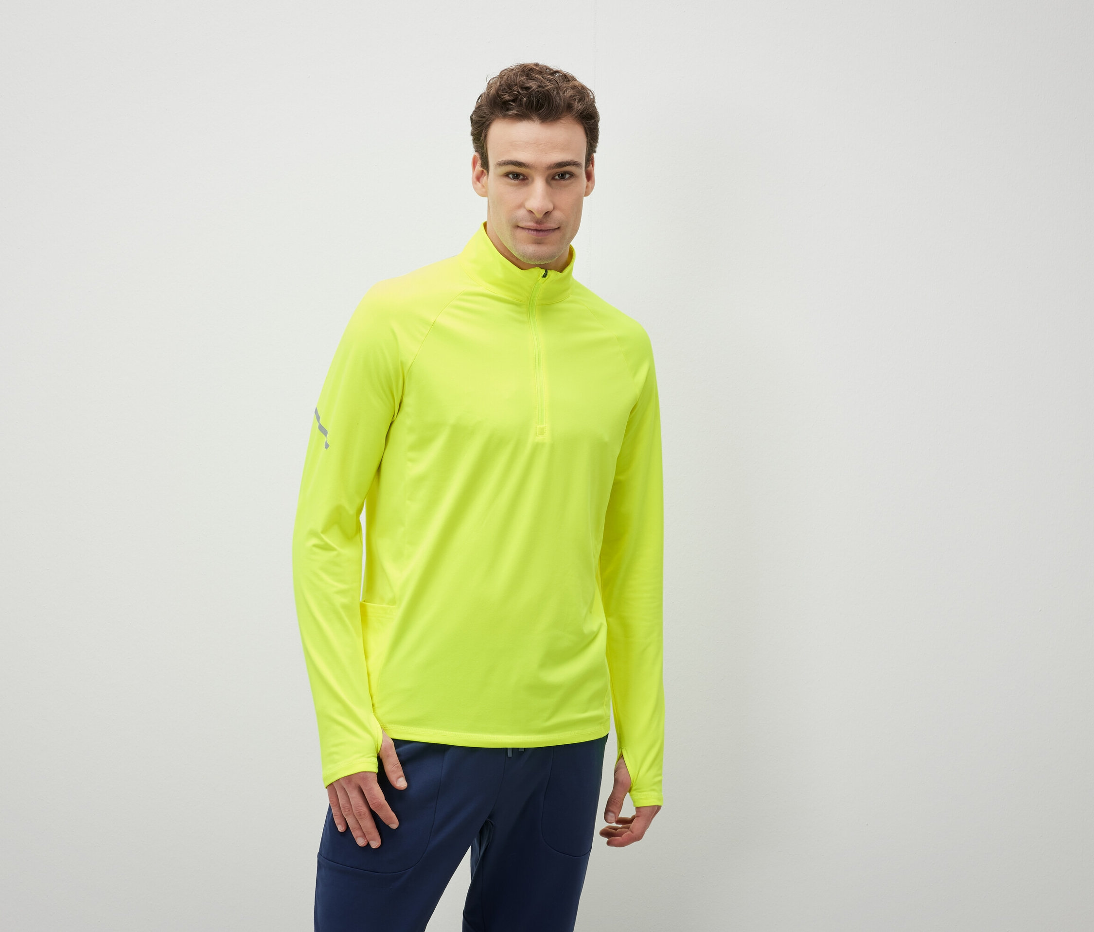 Mann trägt ein neongelbes Langarmshirt und dunkelblaue Hosen.