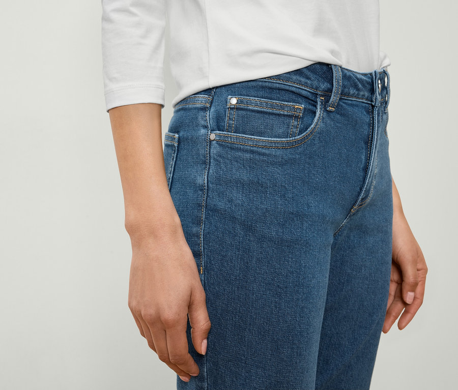 Frau trägt blaue Jeans und ein weißes Hemd.