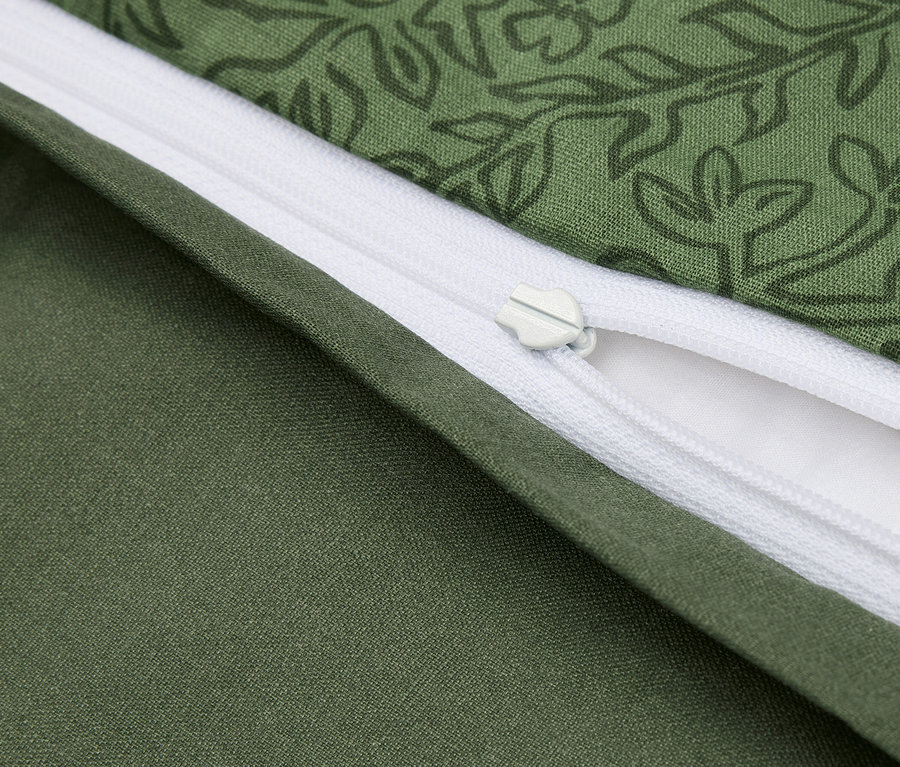 Detailaufnahme eines grünen Bettbezugs mit Blumenmuster und weißem Reißverschluss.