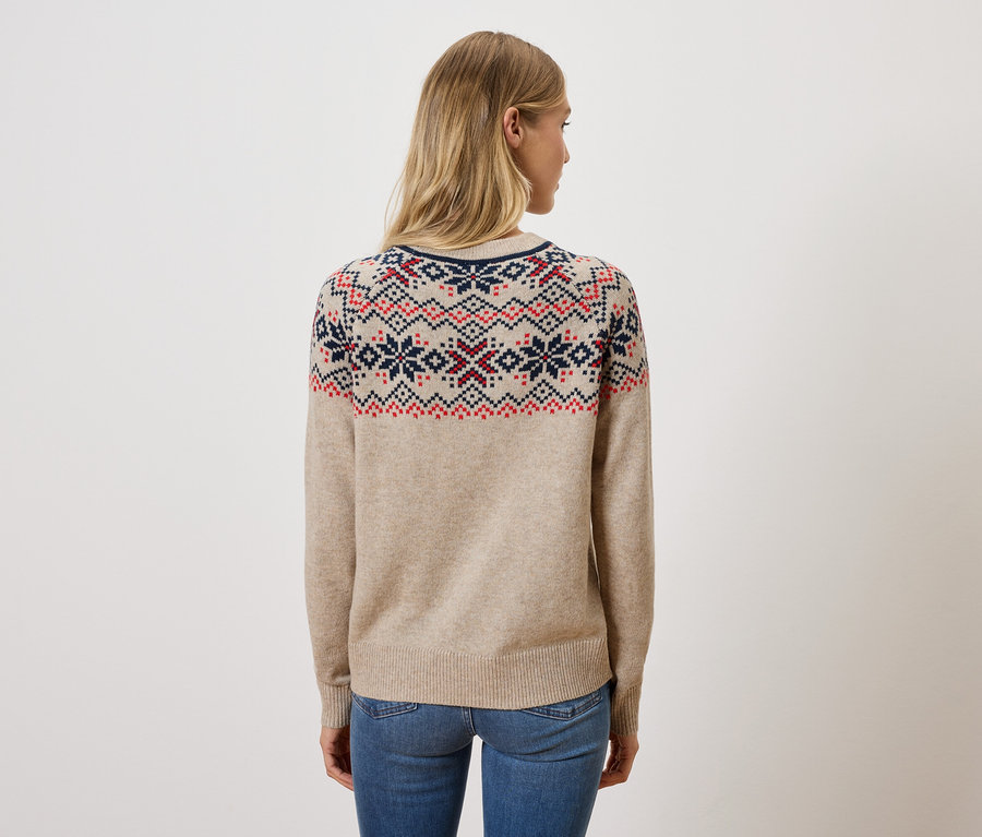 Frau mit dem Rücken zur Kamera trägt einen beigen Pullover mit Muster und Jeans.