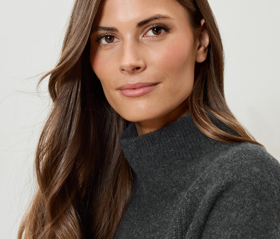 Porträt einer Frau mit braunen Haaren in einem grauen Rollkragenpullover.