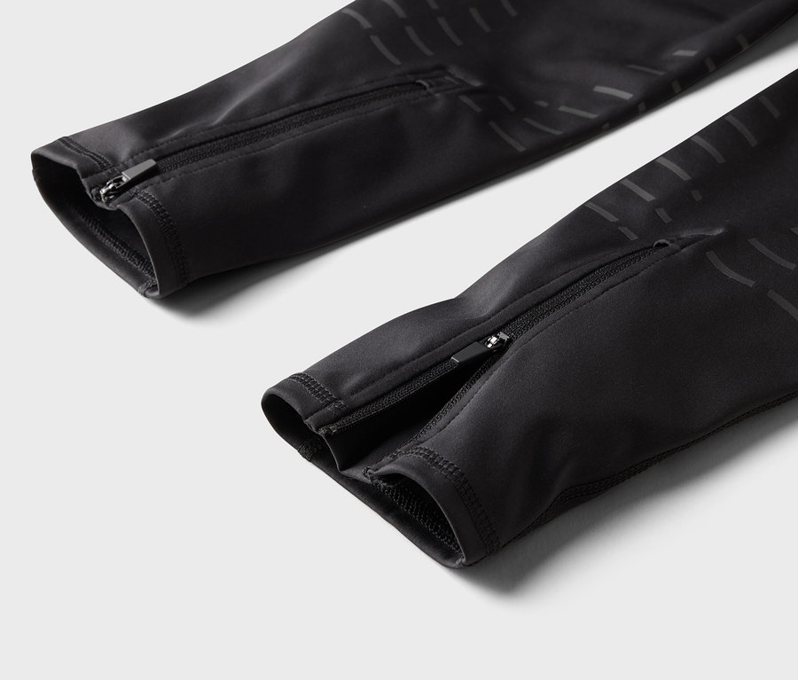 Detailaufnahme von schwarzen Hosen mit Reißverschlüssen an den Hosenbeinen.