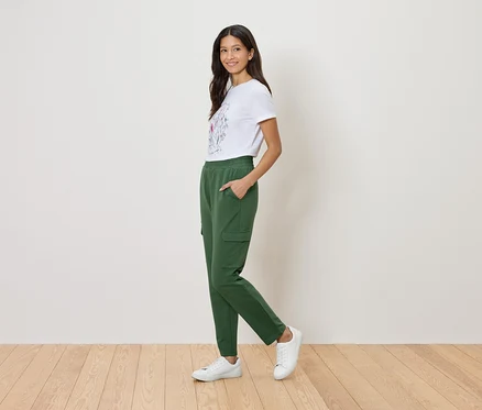 Frau mit weißem T-Shirt mit Blumenmuster und grüner Cargohose.