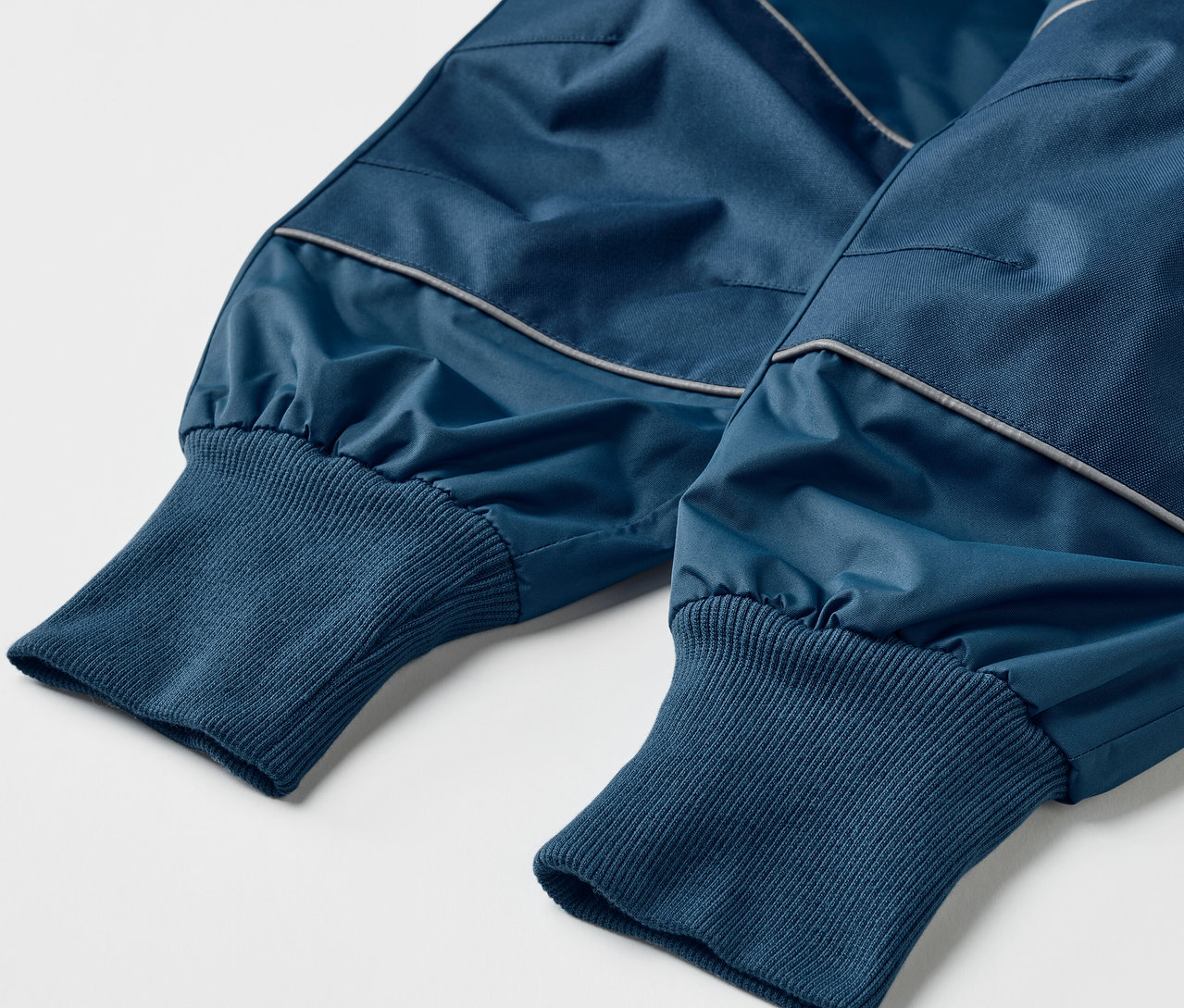 Detailaufnahme einer blauen Kinder-Regenhose mit Mitwachsfunktion.