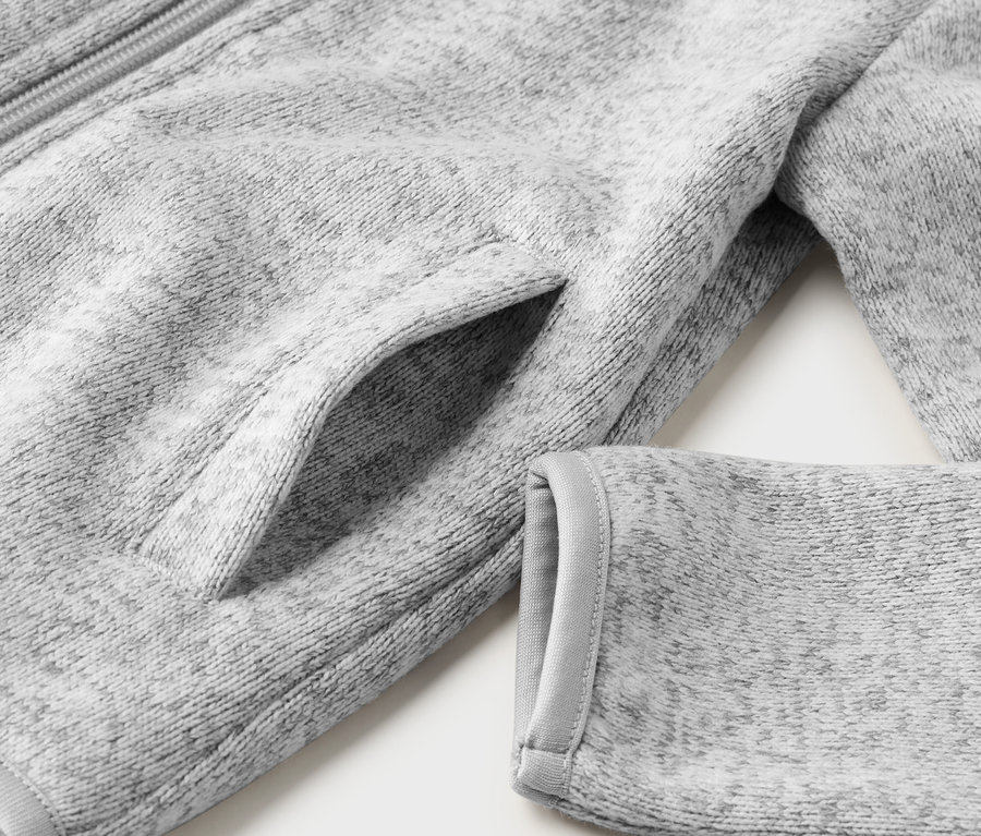 Detailaufnahme einer grauen Kinder-Strickfleecejacke mit Tasche und Ärmel.