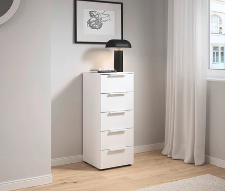 Weißer Schrank mit fünf Schubladen steht neben einer Wand mit einem Bild und einer Lampe.
